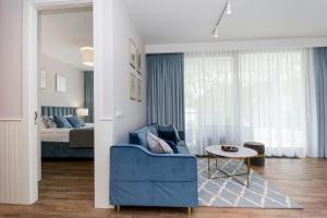 a living room with a blue couch and a bed at Blue Rentyear Apartments in Gdańsk