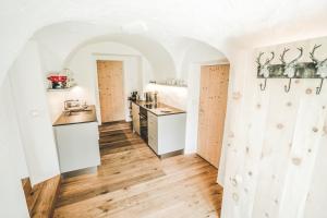 a kitchen with white walls and wooden floors and counters at Il Maschun im historischen Engadinerhaus in Scuol