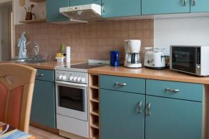uma cozinha com armários azuis e um forno com placa de fogão em Vorbeischauen in Plauen 2 em Plauen