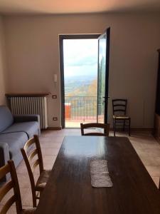 ein Wohnzimmer mit einem Tisch und einem großen Fenster in der Unterkunft Appartamento con vista sulle colline Toscane in Montespertoli
