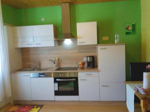 a kitchen with white cabinets and a green wall at Weingut Matthias Dauns in Reil