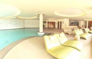 a hotel lobby with a pool and white furniture at Rio Stava Family Resort & Spa in Tesero