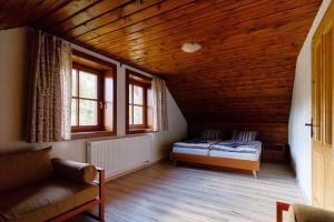 a bedroom with a bed and two windows and a couch at Chata Lienka in Lazisko