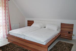 Bett mit einem Holzrahmen und weißer Bettwäsche in der Unterkunft Ferienwohnung Bergblick Xanten in Xanten
