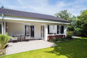 a house with a patio and a lawn at NordseeHeide-Lodges Cuxhaven in Cuxhaven