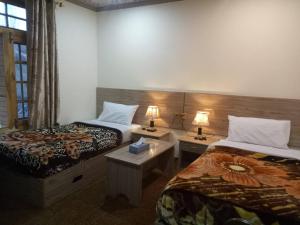 a hotel room with two beds and two lamps at Hunza Holiday Inn in Baltit