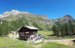 un edificio in un campo con una montagna sullo sfondo di La Piana Appartamenti ad Alpe Devero