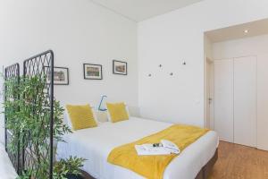 a bedroom with a large white bed with yellow pillows at Monchique´s Balcony in Porto