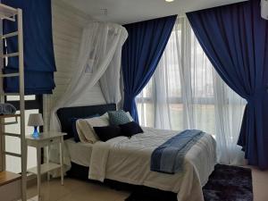 1 dormitorio con 1 cama con cortinas azules y ventana en H2O Residences Marine Blue by ADDS, en Petaling Jaya