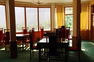 - une salle à manger avec des tables, des chaises et des fenêtres dans l'établissement Karim Hotel, à Hunza