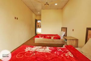- une chambre avec 2 lits dotés de draps rouges et d'une couverture rouge dans l'établissement Karim Hotel, à Hunza