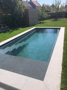 a swimming pool with blue water in a yard at De Lanterfanters Vakantiehuis Jef in Nieuwpoort
