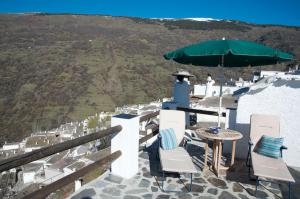 a patio with a table and chairs and an umbrella at Casa Josefa in Capileira