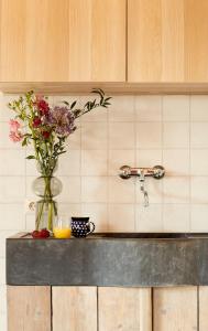 a vase of flowers on a counter with a sink at Het Knechthuys in Baarlo