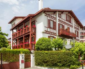 een gebouw met rode bloemen op de balkons bij Hotel Villa Catarie in Guéthary