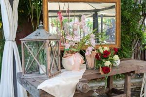 - une table avec des fleurs, une lanterne et un miroir dans l'établissement Principato Di Ariis, à Rivignano