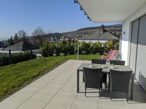 eine Terrasse mit einem Tisch und Stühlen auf einer Terrasse in der Unterkunft Ferienwohnungen Pellenzblick - Wohnen auf Zeit - in Nickenich