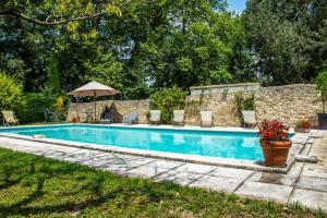 una piscina con sillas y sombrilla en Stunning farmhouse with heated private pool in Provence en Pernes-les-Fontaines