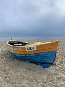 una barca blu seduta su una spiaggia sabbiosa di OW POLAM a Stegna