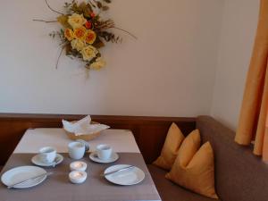 ein Tisch mit Teller und Tassen und ein Blumenstrauß in der Unterkunft Appartments Innerhofer in Riffian