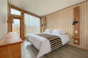 - une chambre avec un grand lit et une grande fenêtre dans l'établissement AKA Patagonia, à Puerto Natales