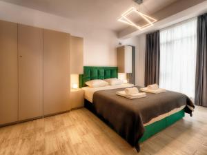 um quarto com uma cama grande e uma cabeceira verde em Sunway - Pool & Spa Beach Resort em Mamaia Nord – Năvodari