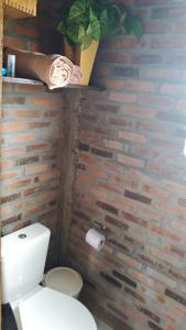 a bathroom with a toilet and a brick wall at Hostel Holztel in Sapiranga