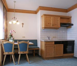 a kitchen with a table and chairs and a cross on the wall at Sportapart Garni Mallaun in See