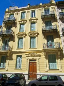 a large yellow building with two cars parked in front of it at Appartement in Nice