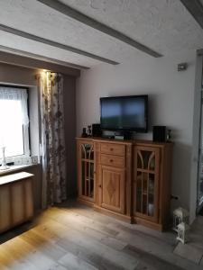 - un salon avec une télévision à écran plat sur une armoire en bois dans l'établissement Ferienwohnung Monecke, à Hürtgenwald