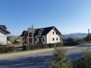 ein weißes Haus mit schwarzem Dach auf einer Straße in der Unterkunft Apartament Nowe Maniowy in Maniowy