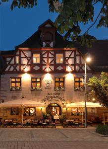 a building with tables and umbrellas in front of it at Alte Nagelschmiede in Altdorf bei Nuernberg