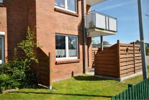 een stenen huis met een houten hek en een balkon bij Medemufer in Otterndorf