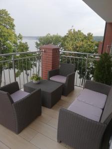 d'un balcon avec des chaises en osier et une table. dans l'établissement Apartament z widokiem na Jezioro, à Olecko