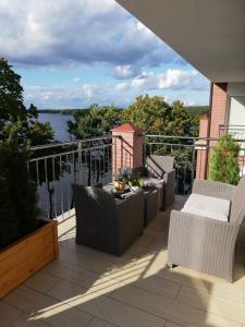 d'un balcon avec des chaises et une table offrant une vue sur l'eau. dans l'établissement Apartament z widokiem na Jezioro, à Olecko