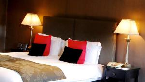 a hotel room with a large bed with red pillows at Swinfen Hall Hotel in Lichfield