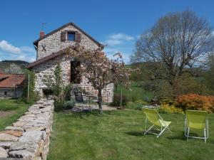 une maison en pierre avec 2 chaises dans la cour dans l'établissement côté jardin, à Saint-Clément