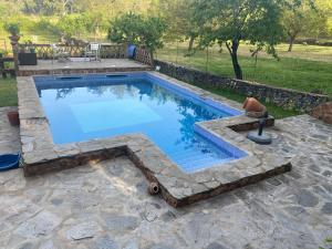 uma piscina com um passadiço de pedra ao redor em Huerto Los Castaños em Los Marines
