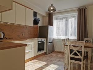 cocina con armarios blancos, mesa y sillas en Apartament KAKADU, en Konin