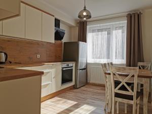 a kitchen with white cabinets and a table and chairs at Apartament KAKADU in Konin