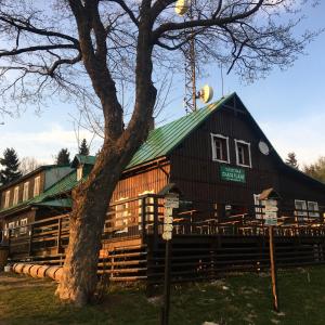 a large wooden building with a green roof at Turistická Chata Pláně in Český Dub