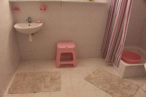 uma casa de banho com um lavatório e um banco rosa em Domek Letniskowy nad Jeziorem Tumiany em Bartołty Wielkie
