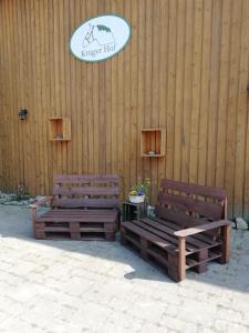 2 bancos de madera sentados junto a una pared de madera en Krügerhof Lübbersdorf, en Oldenburg in Holstein