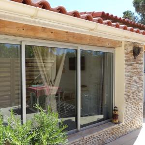 une véranda avec des portes coulissantes en verre sur une maison dans l'établissement Gîte Les Lauriers Roses, à Marseillan