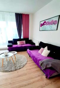 a living room with two purple beds and a table at Riviéra Lipno 510/17 in Lipno nad Vltavou