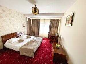 ein Schlafzimmer mit einem Bett und einem roten Teppich in der Unterkunft Pensiunea de Vis in Buftea