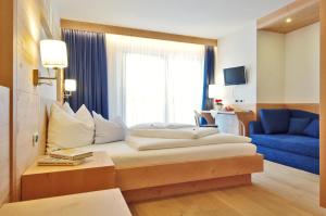 a hotel room with a bed and a blue couch at Garni Cristin & Dep Antina in Colfosco