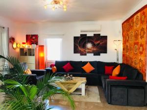 a living room with a black couch and orange pillows at Villa Sunkiss Algarve Carvoeiro in Carvoeiro