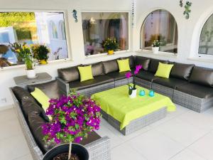 a living room with a black leather couch and flowers at Villa Sunkiss Algarve Carvoeiro in Carvoeiro