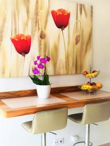 a table with two red flowers and a bowl of fruit at Villa Sunkiss Algarve Carvoeiro in Carvoeiro